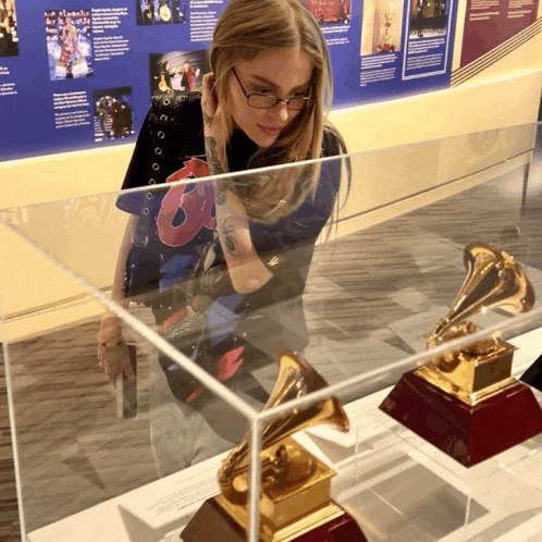 a woman is looking at a grammy trophy in a case