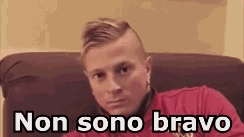 a man in a red shirt is sitting on a couch with the words non sono bravo written below him .