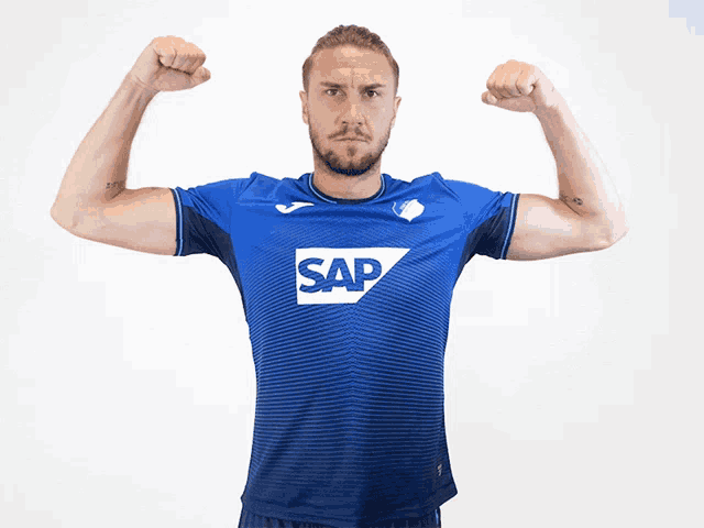 a man flexes his muscles wearing a blue shirt with the word sap on it