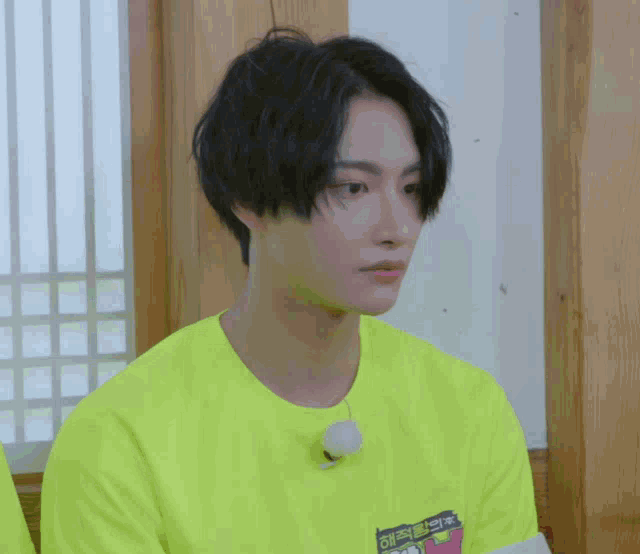 a young man wearing a neon yellow t-shirt with a sticker on it that says ' a ' on it