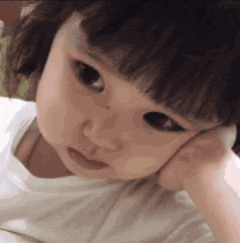 a close up of a baby 's face with a hand on her face