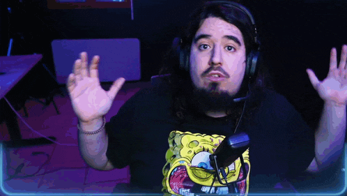 a man wearing headphones and a spongebob shirt holds his hands up