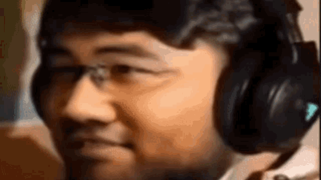 a man wearing headphones and glasses looks at the camera .