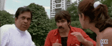a man in a red shirt is talking to a woman in a park .