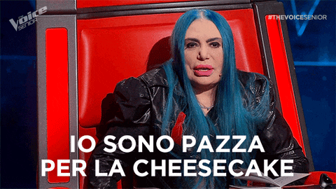 a woman with blue hair is sitting in a chair with the words " io sono pazza per la cheesecake " above her