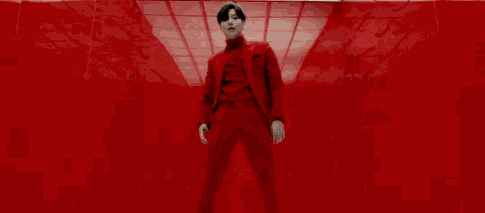 a man in a red suit is standing in a red room with a red ceiling .