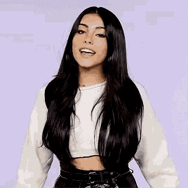 a woman with long black hair is wearing a crop top and black pants .
