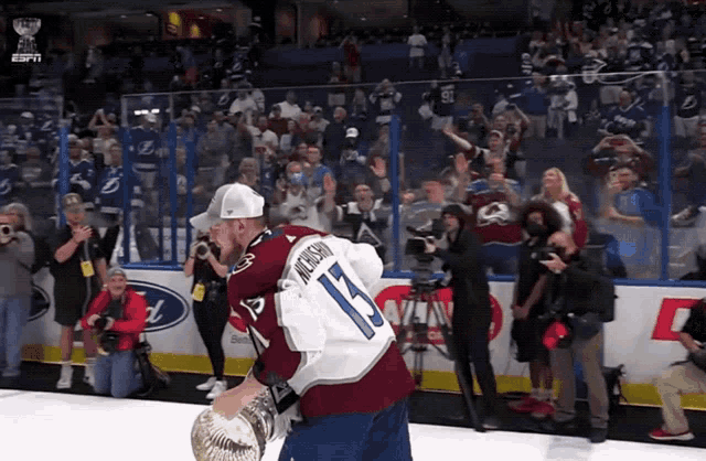 a hockey player with the number 15 on his back is holding a trophy