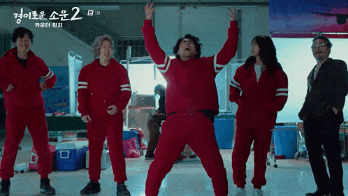 a group of people in red jumpsuits are standing in front of a sign that says ' 2 '