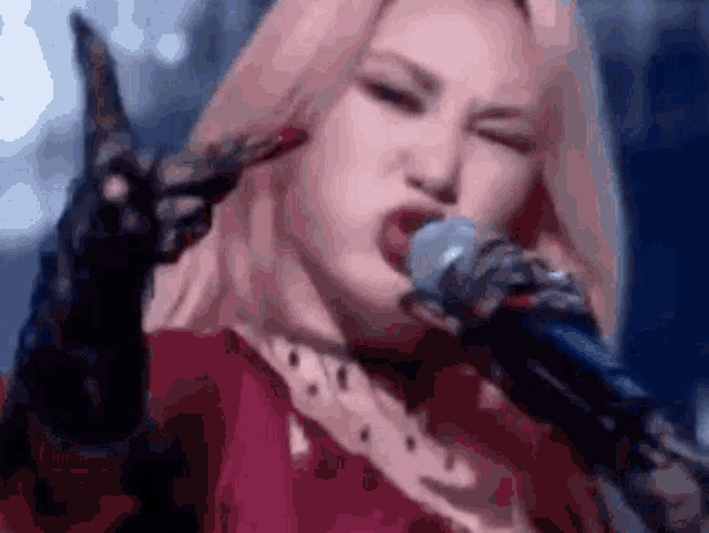 a woman in a red dress is singing into a microphone and making a funny face .