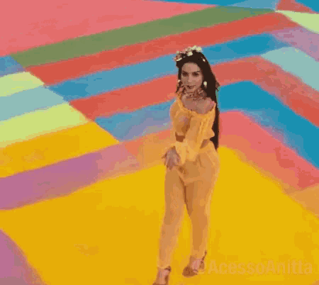 a woman in a yellow outfit is dancing on a colorful floor .