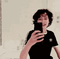 a young man is taking a selfie in a bathroom mirror .