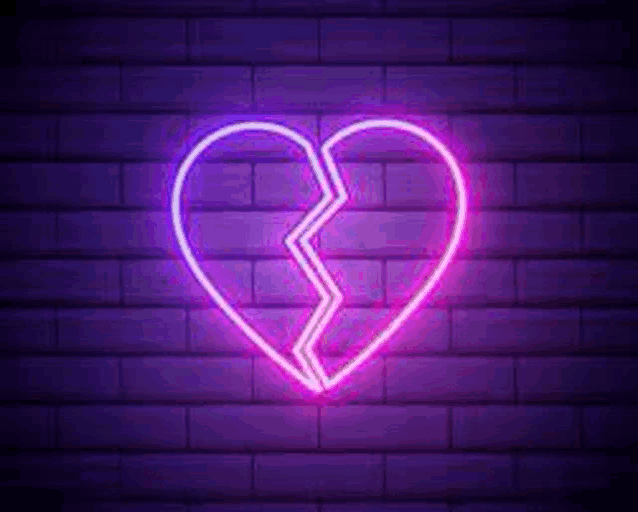 it is a neon sign of a broken heart on a brick wall .