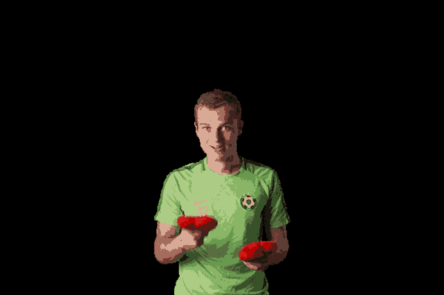 a man in a green shirt with the number 12 on it is holding two red hearts