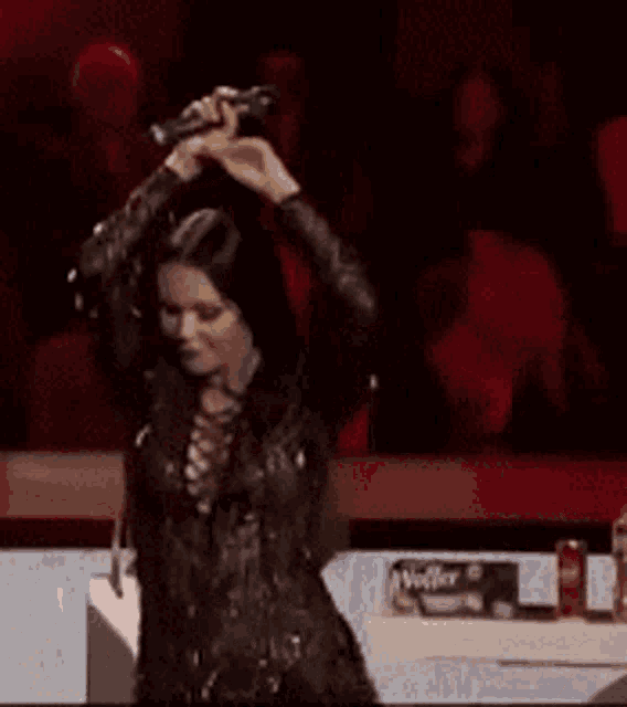 a woman in a black dress is holding a microphone in her hand