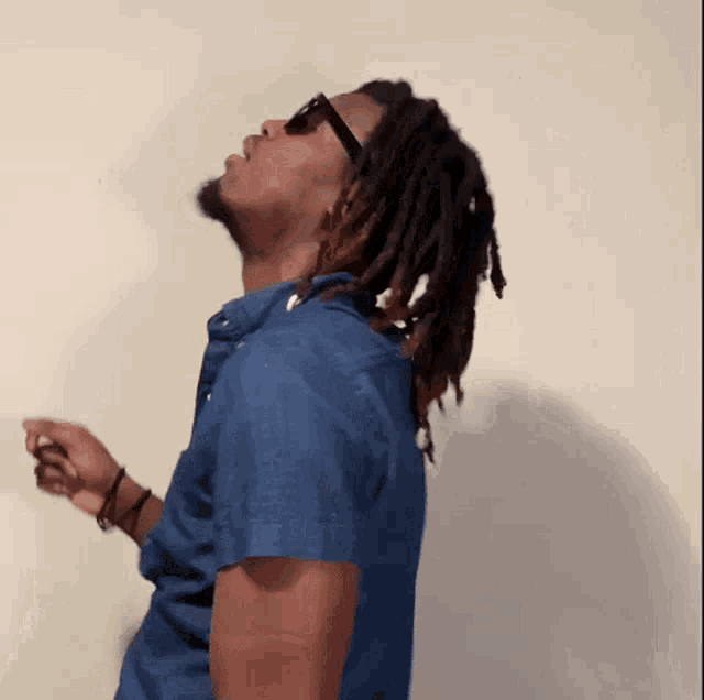 a man with dreadlocks wearing sunglasses and a blue shirt is dancing
