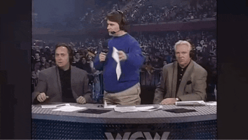 a man in a blue sweater is holding up a piece of paper in front of a wow sign