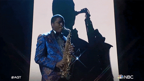 a man in a suit is playing a saxophone in front of a nbc logo