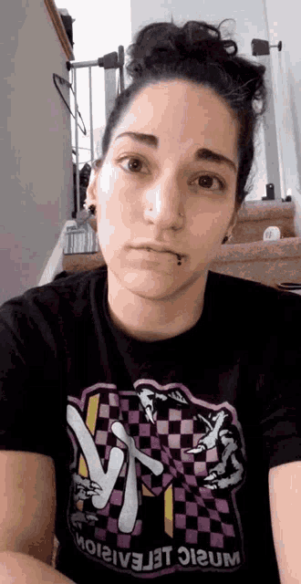 a woman wearing a black t-shirt with a checkered pattern has a nose ring