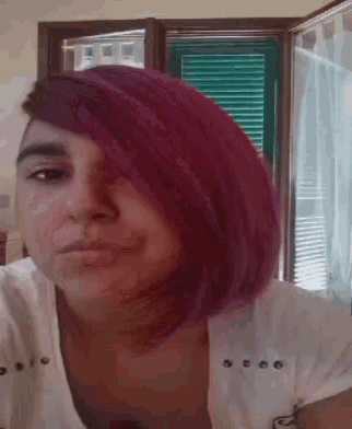 a woman with purple hair and a white shirt is making a face