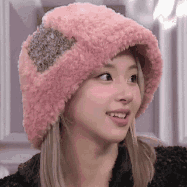 a close up of a woman wearing a pink furry hat and smiling .