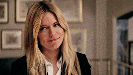 a woman with long blonde hair is wearing a black jacket and white shirt and smiling .