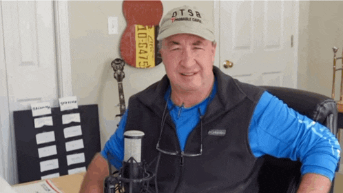 a man wearing a hat that says dtsb sitting in front of a microphone