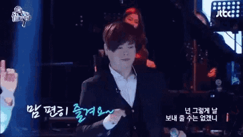 a man in a suit is holding a microphone in front of a screen that says jtbc