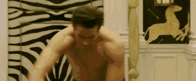 a man without a shirt is standing in front of a zebra print wall