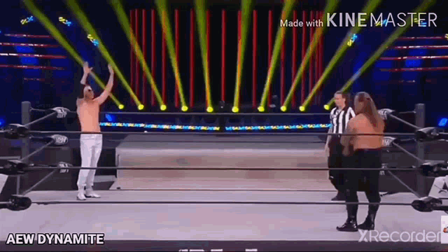 a wrestler is standing in a wrestling ring with his hands in the air .