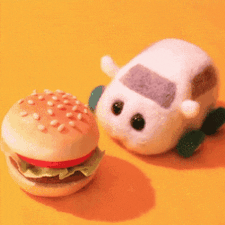 a stuffed animal car is eating a hamburger on a yellow background .