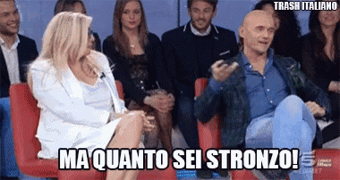 a group of people are sitting in red chairs and a woman is saying ma quanto sei stronzo !