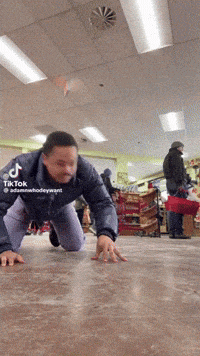 a man is crawling on the floor in a store with tiktok written on the bottom