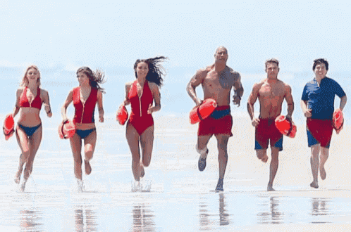 a group of lifeguards running on a beach