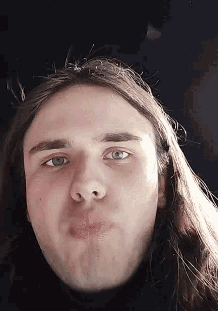 a young man with long hair is making a face