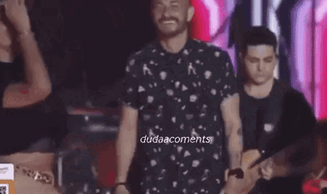 a man and a woman are dancing on a stage with a band in the background .