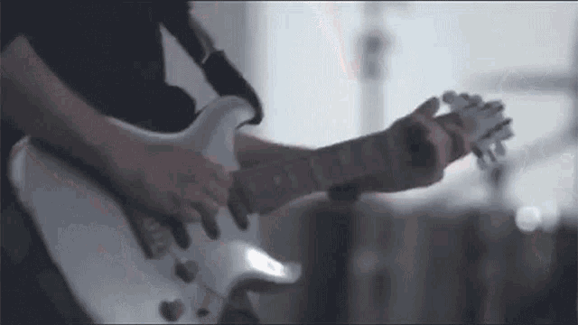 a man is playing a white electric guitar