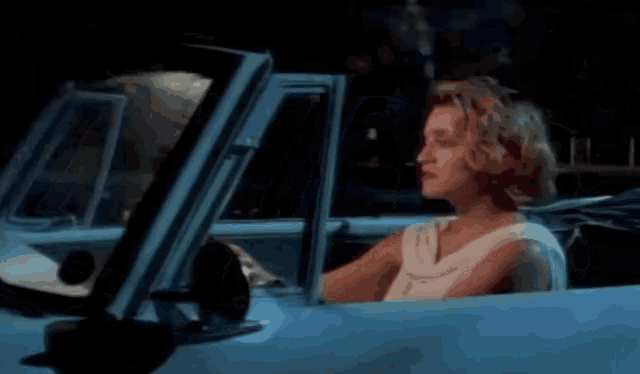 a woman in a white dress is driving a car