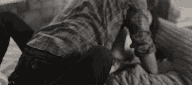 a man and woman are laying on a bed and kissing .