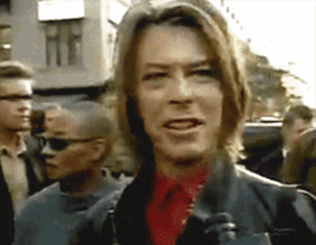 a man with long brown hair is wearing a red shirt and tie