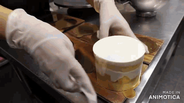 a person wearing gloves is making a cake in a kitchen