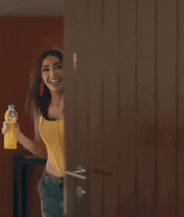 a woman in a yellow top is holding a bottle of juice