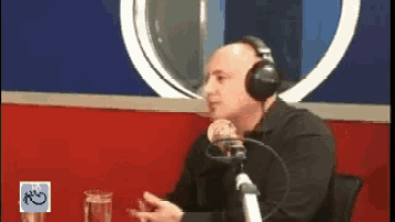 a man wearing headphones is sitting in front of a microphone in a radio studio