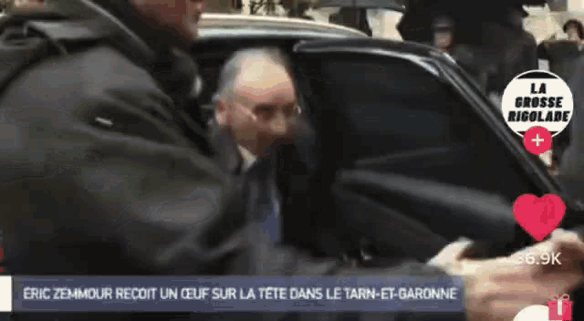 a man getting out of a car with a sign that says la grosse rigolade behind him