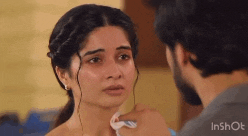 a man is touching a woman 's face with a napkin .