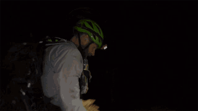 a man wearing a green helmet with a headlamp on