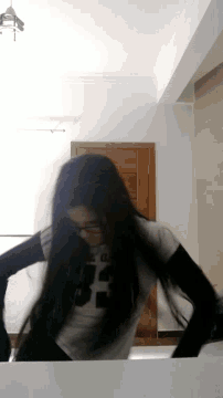 a woman 's hair is blowing in the wind in front of a wooden window