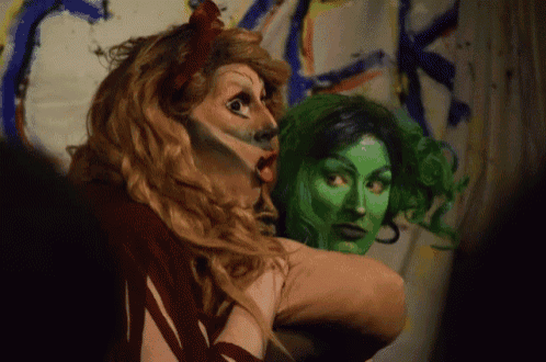 a woman with green paint on her face looks at another woman