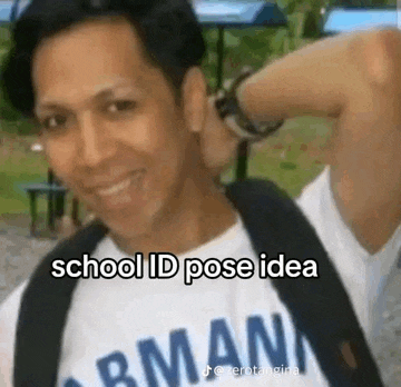 a man wearing a school id pose idea t-shirt is smiling and holding his hand to his head .