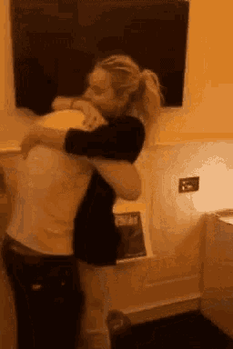 a woman is hugging a man in a room with a tv on the wall .